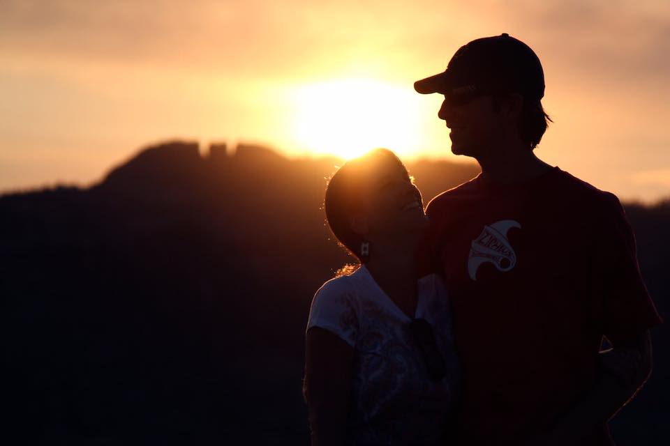 Silhouette image of Julie and her husband Todd in a baseball cap with the sunset behind them.